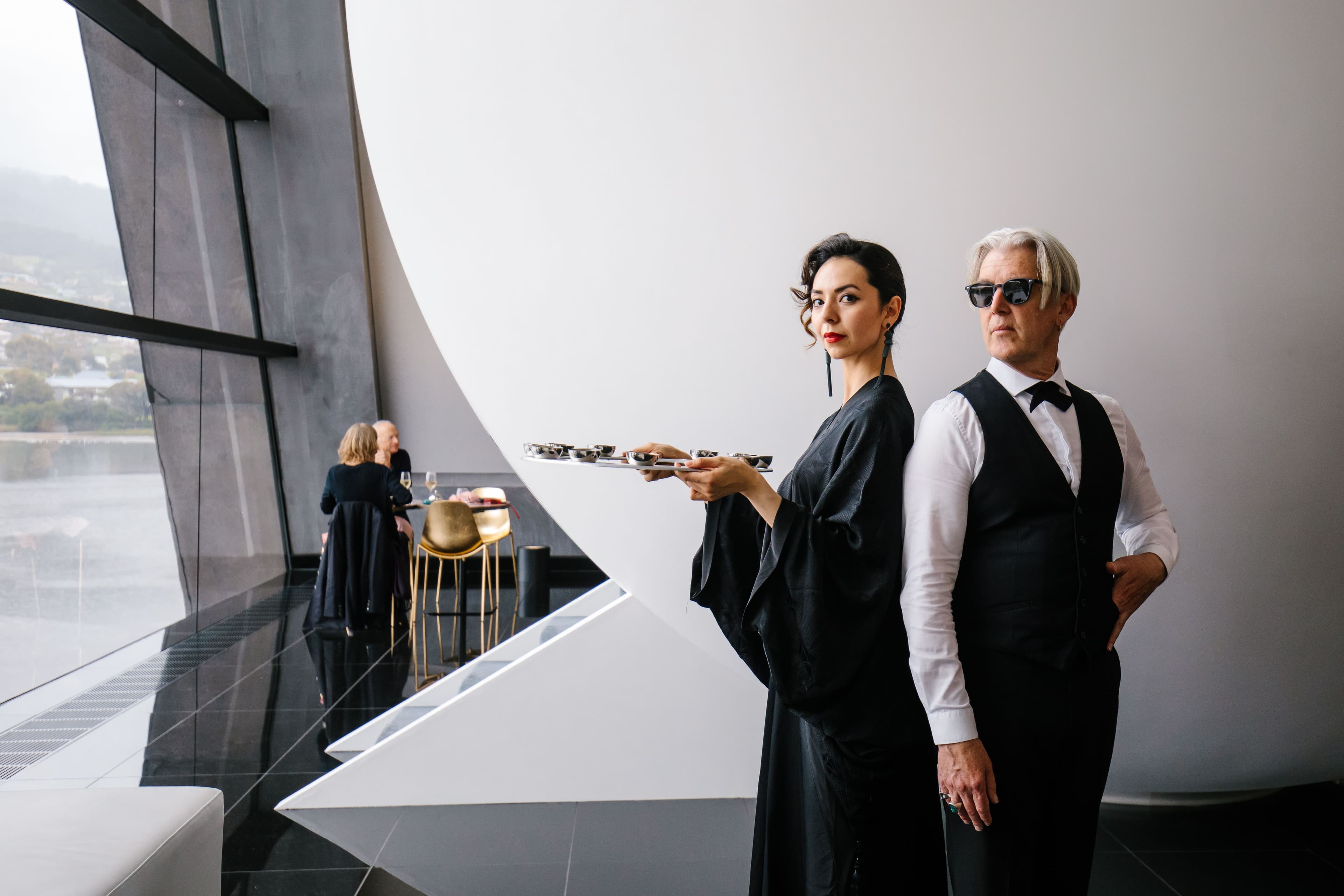 Two elegantly dressed butlers stand posed ready to serve.