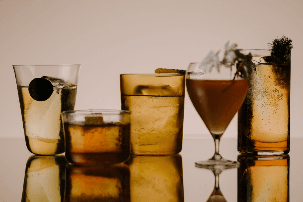 5 glasses of different shapes containing ice and a range of refreshing looking cocktails