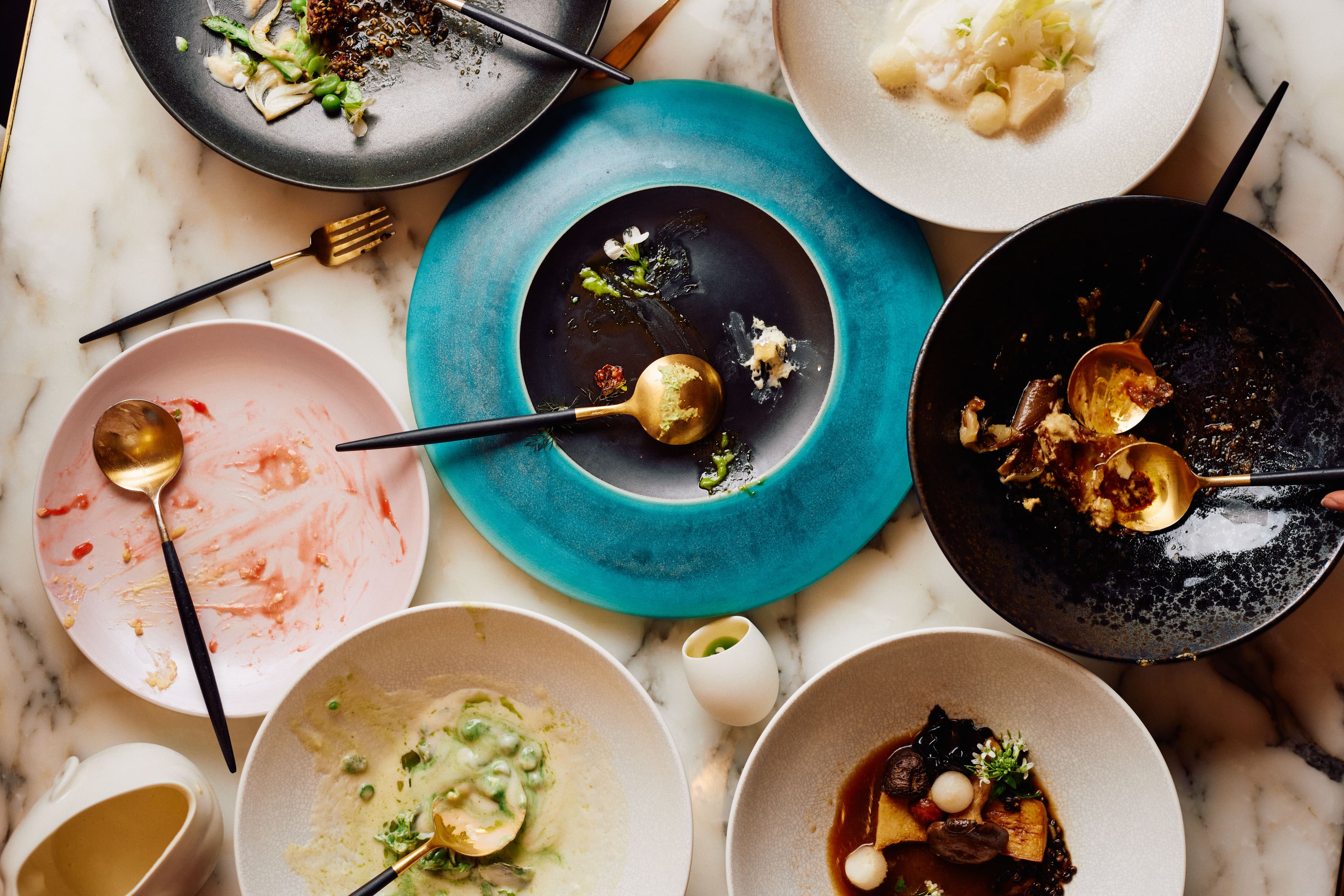 Birds eye view of a marble table top with thoughtfully plated food in various states of consumption