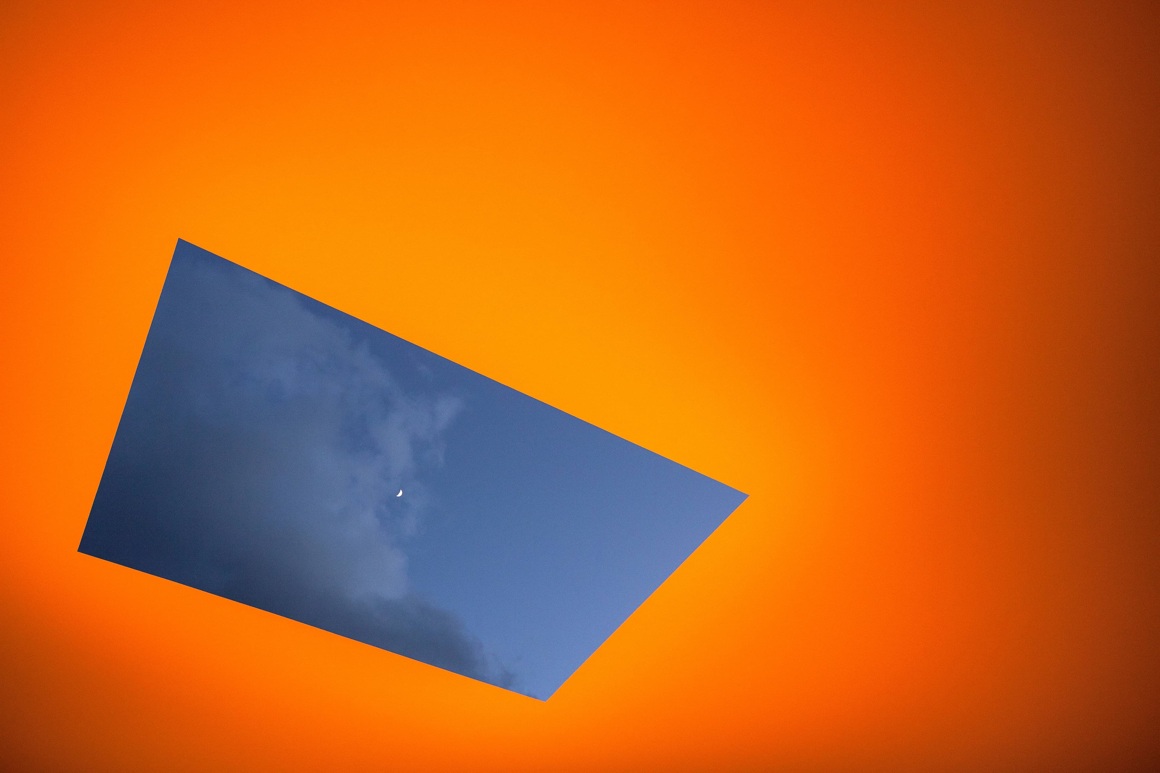 An orange lit roof with a hole showing a cloudy, dusky sky.